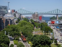 A transfer with GP9's CN 7226 & CN 4115 for power is leaving the Port of Montreal on a sunny afternoon, as viewed from a tower that is part of the Pointe-à-Callière Museum. In the background at left is the Bonsecours Market and the Molson Plant (soon to move to the South Shore) and at right is the Jacques-Cartier bridge, with the amusement park La Ronde barely visible at right.