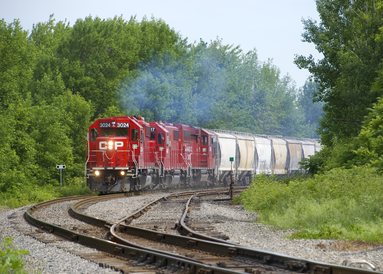 CP F94 with CP 3024, CP 4417 & CP 2205 rounds a curve on CP's Lacolle Sub, passing the NJ Yard at right as it blows its horn for the nearby Chemin Saint-Ignace crossing.