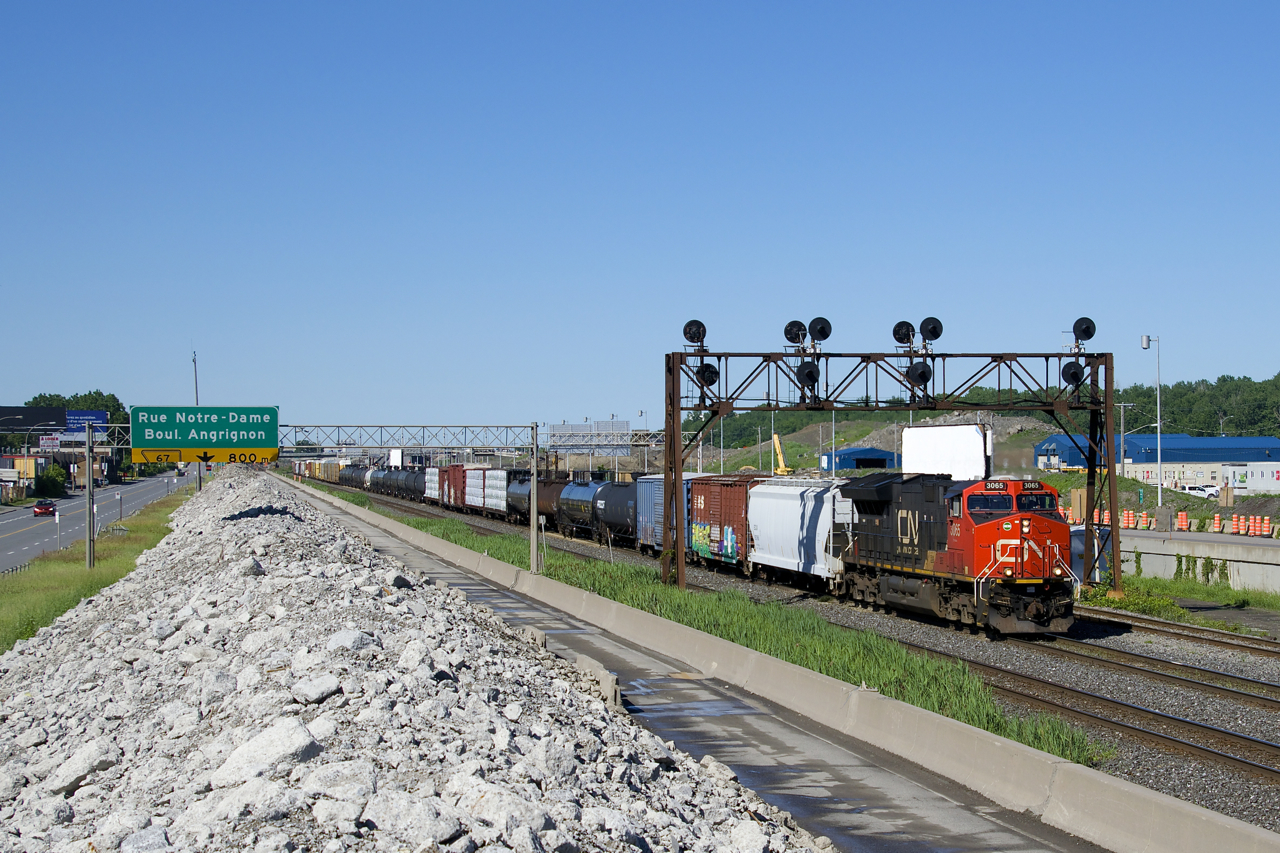 CN 310 is passing the rubble of what was once the westbound lanes of autoroute 20 as it ducks under a vintage signal bridge at MP 5 of CN's Montreal Sub. ES44AC's CN 3065 and CN 3078 (mid-train) provide the horses on this 154-car train.