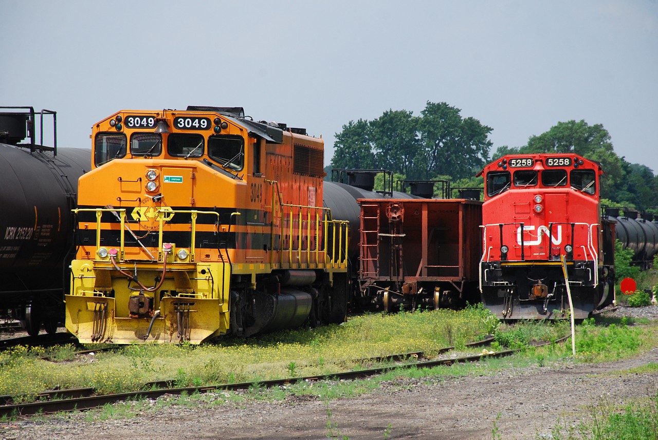 RLHH 3049 and CN 5258 sun themselves on a humid afternoon before a heavy thunderstorm rolled through.  CN 5258 was set off by CN 434 on Sunday evening after its rear draw bar broke when the train began pulling after working the yard.  RLHH 3049 was set off Monday night by RLHH 595 after suffering an unknown ailment.  Mechanics from their respective railroads attended to the locomotives on Tuesday, so hopefully both have been repaired and will soon return to service.  There can't be too many opportunities to get two Canadian "safety cabs" belonging to two different railroads side by side.  CN 5258 is one of two SD40-2Ws used as LNG test units and retains the flared radiators.