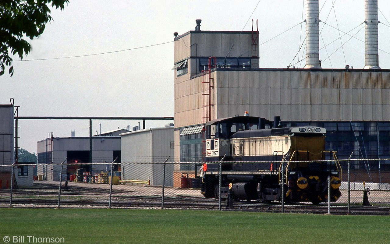 GMD shop switcher 113 (one of the former EMD demo SW1500 units) is pictured outside the GMD London locomotive assembly plant, outfitted with buffers to handle new SNTF Algerian export locomotives under construction (one is visible inside the plant).

Built in 1971 was a demo unit and formerly used as a shop switcher at EMD's La Grange IL plant, the 113 only lasted about two years as a shop switcher at London before it was traded with Essex Terminal Railway (and became ETR's 107) for their SW8 102, due to issues with tight trackage at the plant.