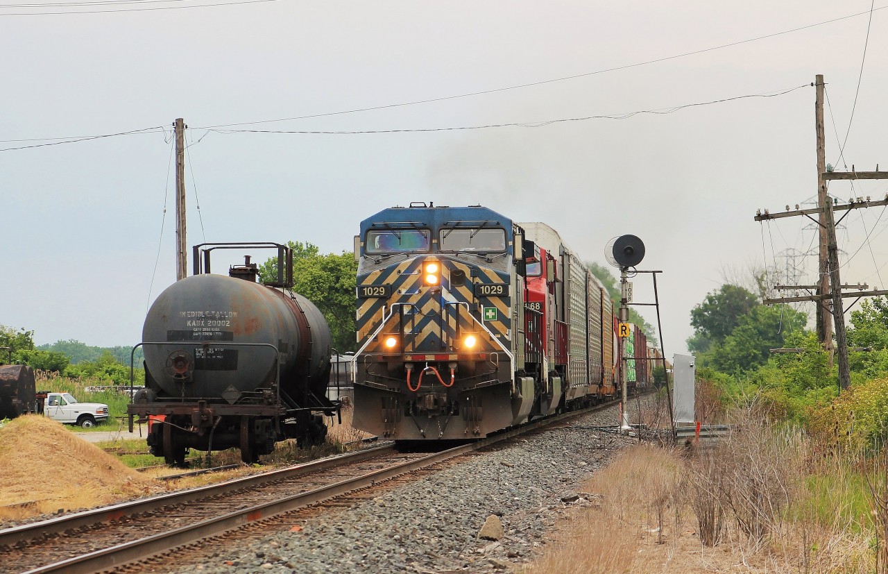 A late 141 passes the intermediate signal at MP 100 and a forgotten tank car left land locked in an unused siding. CP used to service a business here several years ago but after a fatal accident involving a tank car occurred on the property, they no longer receive rail service.