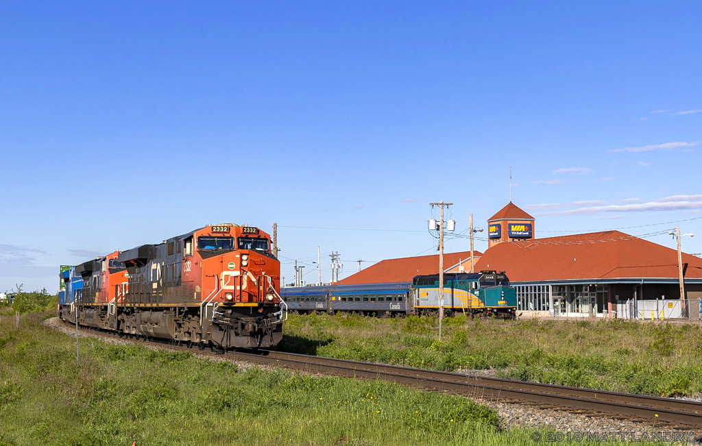 A late CN Q120 passes by the VIA station at Moncton, New Brunswick. Parked near the station is the power and 4 cars for the CN Safety Days passenger train, which will run between CN's Gordon Yard and the VIA station.