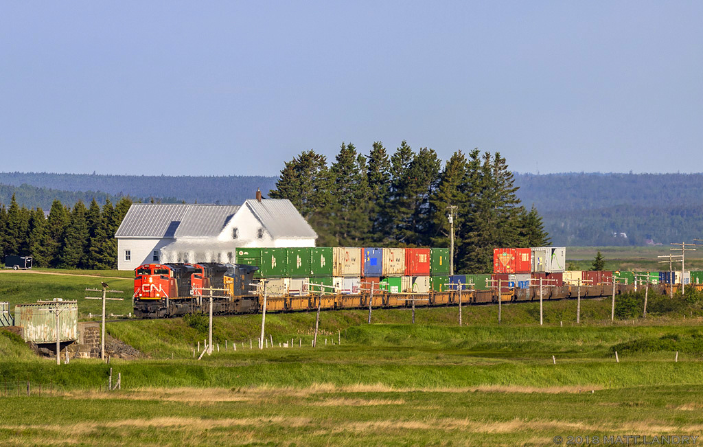 CN 8909 leads stack train Q120 eastbound, as they cross over from New Brunswick, into Nova Scotia, and are approaching Amherst, Nova Scotia, near sunrise.
