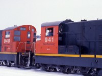 RAILROADER ON THE ROCK. Longtime Engineer Ray Boyd carefully applies the throttle of leading unit NF210 #941 of Terra Transport Mixed Extra 941 West to couple some additional container flats at Grand Falls during Christmas week of 1987. The 1200 horsepower unit with a CN Class of GR-12-x and built by GMD of London Ontario, along with sister 940, was one of 9 in the final order shipped to Newfoundland in 1960. This photo gives an excellent view of the unique end cabs of the NF210's and the very similar NF110's. Its new paint and the excellent maintenance carried out by the shop crews in St. John's belies the fact that these two units were 27 years old. Always well spoken and a consummate gentleman, Ray would later be the 'Mystery Guest' on CBC's 'Front Page Challenge' when the top news story was the shutdown on the Newfoundland Railway!