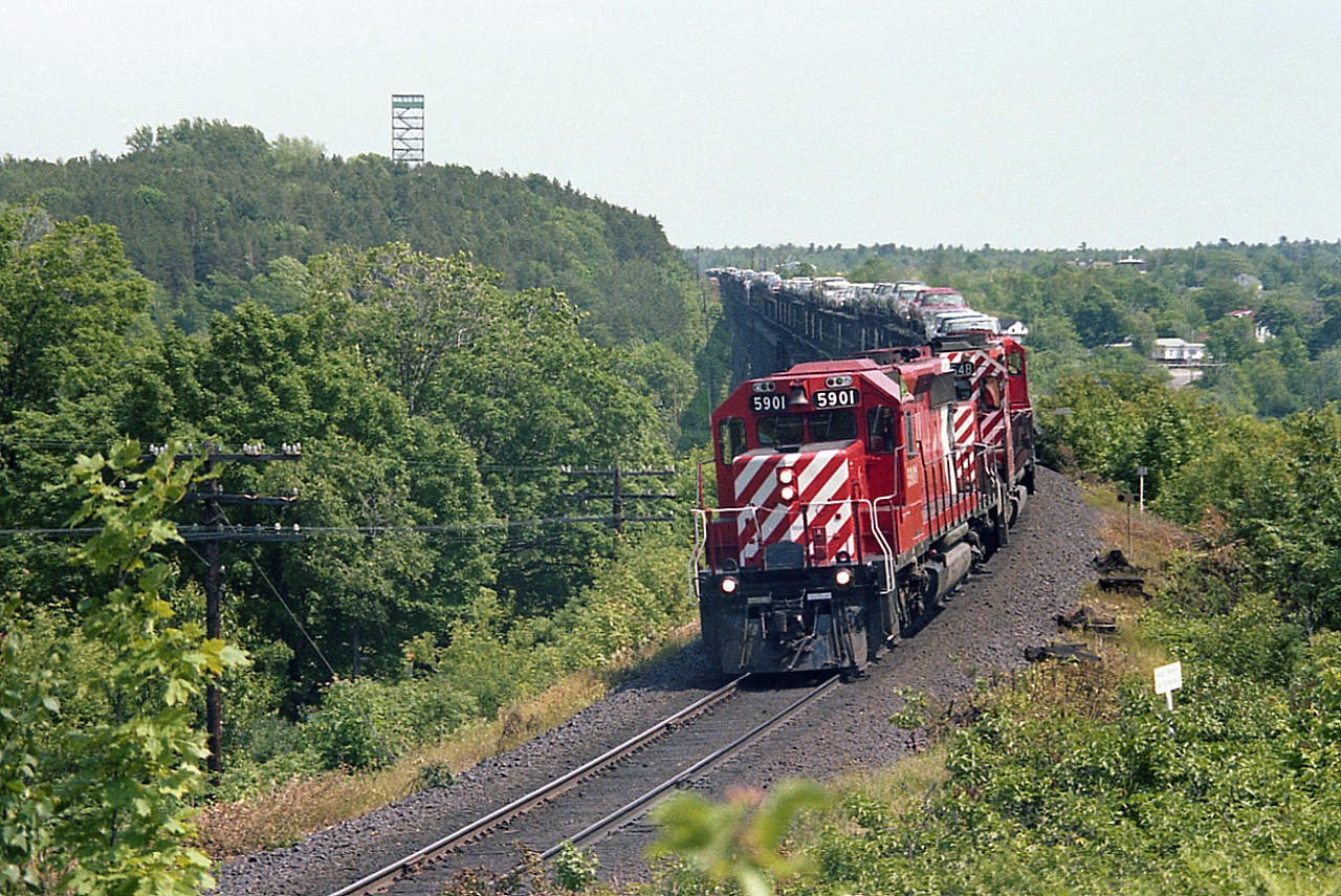 Northbound, coming off the huge Parry Sound trestle and about to round the curve on approach to the station, CP 5901 leads 5548 and a unknown number with a load of vehicles stretching as far back as the eye can see. This great little location for shooting has long ago succumbed to the onslaught of vegetation. However, the fire tower in the background is still viable, but due to directional running with CN and CP sharing assets there rarely is a preferred southbound move seen from that location any more.