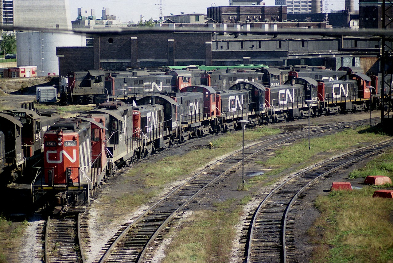 Wandering down to Toronto, specifically around the sprawling facility as seen from the Spadina bridge; one could see a vast array of locomotives most days. Here is a typical view from a Wednesday afternoon in late Sept 1976.
Can be seen; from the left: CN 1323 & 1249. In the rear: CN 4103 and an unidentified S-13. In front, 8521 and 8514. And in a row along the foreground are: CN 4567, 4519, 8226, 8228, 8227 and 8229 and almost out of sight, 8220. The MLW S-7 8200 series seen here were used mostly in and around the Spadina terminal, helping with the make up of CN passenger trains. All these units were gone from the roster by 1985.  Note location of image, as base of CN Tower can be seen in upper left.