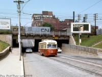 On a sunny Summer afternoon in 1967, we find TTC PCC 4773 (an A-14 class car acquired secondhand from Kansas City) working the St. Clair route, heading eastbound on St. Clair Avenue West after ducking under the 1932-built rail underpass for the CN Weston and CP MacTier Subdivisions just east of Keele Street. Billboards advertise Ontario Hydro and Goldcrest cigarettes to passing motorists and pedestrians in the area, while silver-painted CN ice refrigerator cars line the yard tracks above in CN's West Toronto Yard, some sporting a fresh coat of paint, others covered with a few year's worth of road grime.
<br><br>
The need for a well-stocked yard full of reefers is evident towering in the background: Swift's Premium Meats, one of the many meat processing facilities in the West Toronto / Junction area that would give Toronto the nickname "Hogtown". Swift's, Gunns, Canada Packers, Maple Leaf Meats, the Ontario Stockyards, and various other smaller players all populated this area in the past, with many rail spurs and sidings to serve their needs including inbound livestock from the west via stock cars, and outbound meat and meat products for distribution in ice and mechanical reefers.
<br><br>
Today after years of gentrification and redevelopment the processing plants and stockyards are gone (except for a few small meat processing operations here and there), replaced with big-box retail plazas, townhouses, and other commercial developments. And while the old PCC's are all retired, streetcars still roll on this part of St. Clair, now served by CLRV's and new Bombardier articulated cars on the Route 512.
<br><br>
<i>Original photographer unknown/not listed, Ektachrome slide from the Dan Dell'Unto coll. with some colour correction/touch-ups</i>.