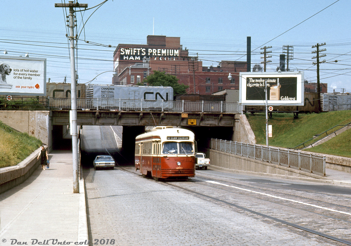 On a sunny Summer afternoon in 1967, we find TTC PCC 4773 (an A-14 class car acquired secondhand from Kansas City) working the St. Clair route, heading eastbound on St. Clair Avenue West after ducking under the 1932-built rail underpass for the CN Weston and CP MacTier Subdivisions just east of Keele Street. Billboards advertise Ontario Hydro and Goldcrest cigarettes to passing motorists and pedestrians in the area, while silver-painted CN ice refrigerator cars line the yard tracks above in CN's West Toronto Yard, some sporting a fresh coat of paint, others covered with a few year's worth of road grime.

The need for a well-stocked yard full of reefers is evident towering in the background: Swift's Premium Meats, one of the many meat processing facilities in the West Toronto / Junction area that would give Toronto the nickname "Hogtown". Swift's, Gunns, Canada Packers, Maple Leaf Meats, the Ontario Stockyards, and various other smaller players all populated this area in the past, with many rail spurs and sidings to serve their needs including inbound livestock from the west via stock cars, and outbound meat and meat products for distribution in ice and mechanical reefers.

Today after years of gentrification and redevelopment the processing plants and stockyards are gone (except for a few small meat processing operations here and there), replaced with big-box retail plazas, townhouses, and other commercial developments. And while the old PCC's are all retired, streetcars still roll on this part of St. Clair, now served by CLRV's and new Bombardier articulated cars on the Route 512.

Original photographer unknown/not listed, Ektachrome slide from the Dan Dell'Unto coll. with some colour correction/touch-ups.