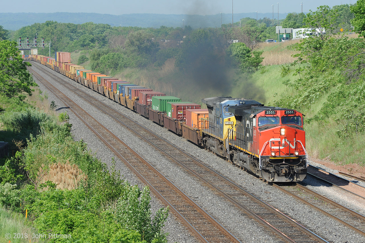 CN train 148 catches nice morning sunshine as the engineer pours on the coal on the upgrade from CN Snake (Road), whose east-side signals are in the distance. GECX 7368 is contributing most of the smoke. Being the day after the US Memorial Day holiday could account for 148 being earlier than usual and having less double stacking.