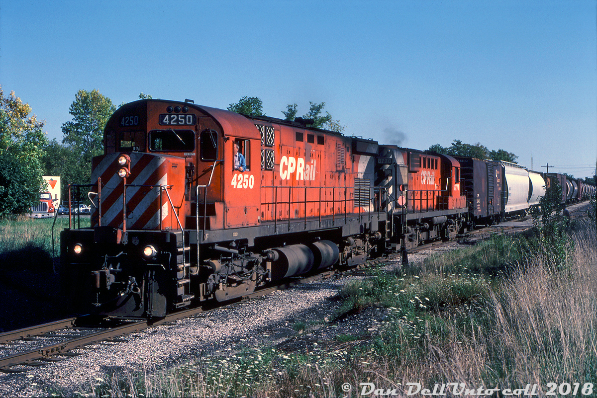 CP C424 4250 and RS18 8770 handle a sizeable train #89 "The Moonlight" northbound through downtown Brampton on the Owen Sound Sub, passing the switch to the Brampton siding/"back track" at Denison Ave. south of the diamond (the switch was later moved south of Denison at some point) as they get ready to cross the CN Halton Sub enroute to Orangeville and beyond.

A nice healthy consist of covered hoppers and boxcars trail the power and stretch out to at least Queen Street (if not further), a far cry from the half-dozen or so cars OBRY typically handles today for the few remaining customers on the line. Hopefully the town of Orangeville and (soon to be) new operator Trillium can work on growing the customer base, or the future of the former CP Orangeville/Owen Sound Sub doesn't look too bright.

Peter Jobe photo, Kodachrome slide from the Dan Dell'Unto collection.