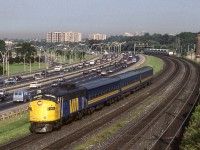 VIA 6541 is eastbound heading towards Toronto Union Station in Toronto on August 9, 1987. Notice both the traffic on the left and the GO train in the background.