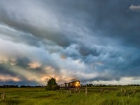 Anticrepuscular rays and mammatus clouds create a dramatic sky as a train comes through the Alberta prairies near Indus, Alberta.