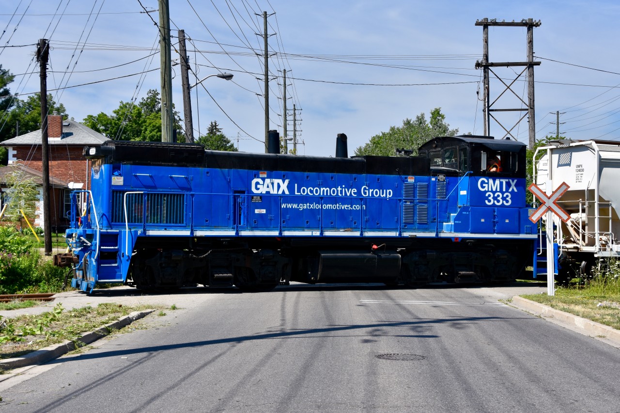 GMTX 333 crosses Railroad st and the CN Halton (out of sight on the south side of the road) at exactly 11:15am as it leads half a dozen freight cars to Mississauga for interchange with CP.