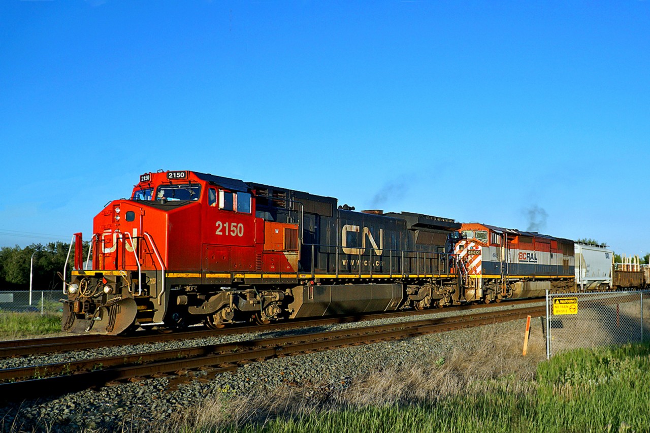 In the evening sun Dash 8-40CW CN 2150 (ex BNSF 830) and Dash 8-40CMu BCOL 4602 lead a westbound freight through Ardrossan.