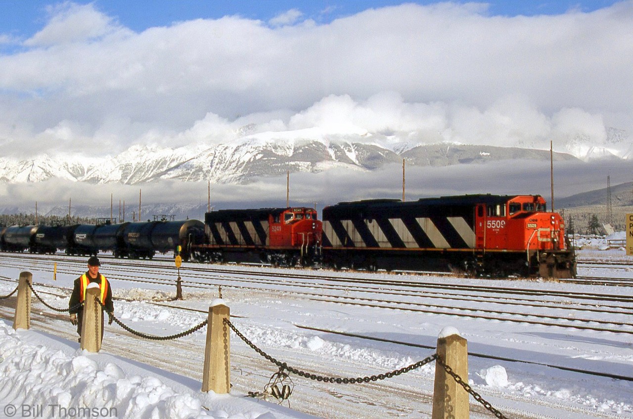 CN SD60F 5509 and SD40-2W 5241 are seen arriving on a westbound freight at Jasper, with the snow-covered mountain ranges and a cloudy white/blue sky making for a very picturesque scene.