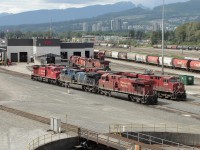 A north-west facing view of CP's Port Coquitlam yard diesel shop and turntable.  In the background part of the city of Port Coquitlam, with some of Coquitlam further up the hillside, and coastal mountains beyond. Nice scenery for a railyard.  Vantage point is the sidewalk of the Coast Meridian Overpass (bridge). <br><br>
In the nearest row are AC4400's CP 9715 and CEFX 1047, then ES44ac CP 8745.  A pair of CP AC4400's and ES44ac CP 8928 are in the next row.  Closer to the diesel shop are AC4400 CP 8614, an SD40-2, and an ES44ac. Looks like GP38ac CP 3011 beside the shop. <br>
