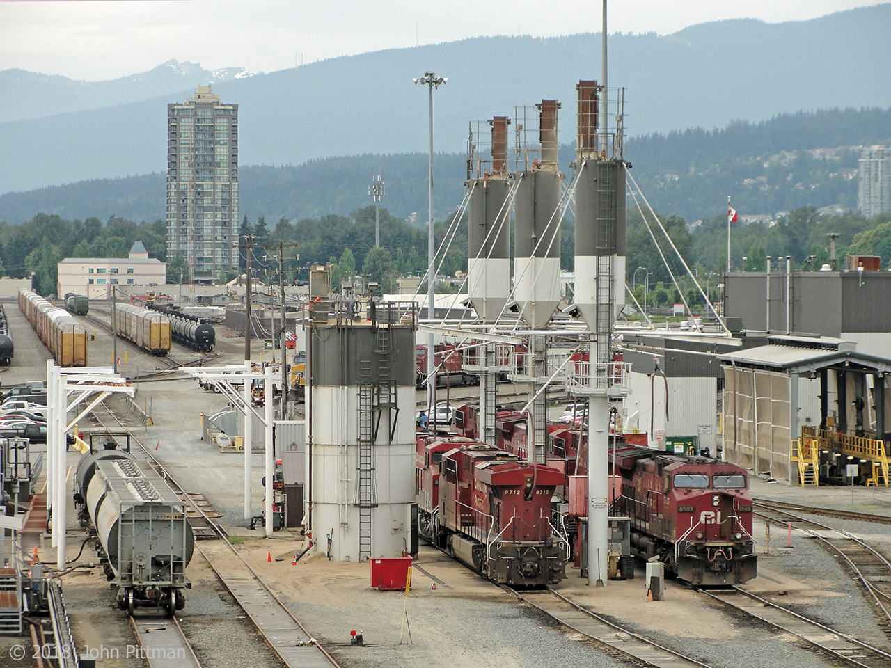The Coast Meridian Overpass suspension bridge crossing CP's main Vancouver-area yard in Port Coquitam BC is a good public place to view a large active rail yard and facilities.  Some drawbacks are end-to-end galvanized steel mesh with 46mm square openings, sidewalk only on the west side, and vibration caused by road traffic.  My photos were obtained with a compact camera whose lens fitted through the mesh, though side and down angles were limited. 
In this west-facing view the tail end of AC4400 CP 8712 and the front of CP8563 can seen at the sand/fuel pad, along with other units. Coastal mountains are prominent to the north west, with plenty of snow at higher elevations this year.