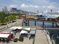 Cruise ship <i>AIDAvita</i> is docked in the Port of Montreal as GP9's CN 7054 & CN 4115 pull some intermodal traffic and baretables destined for track 29 over the Lachine Canal on a sweltering day.