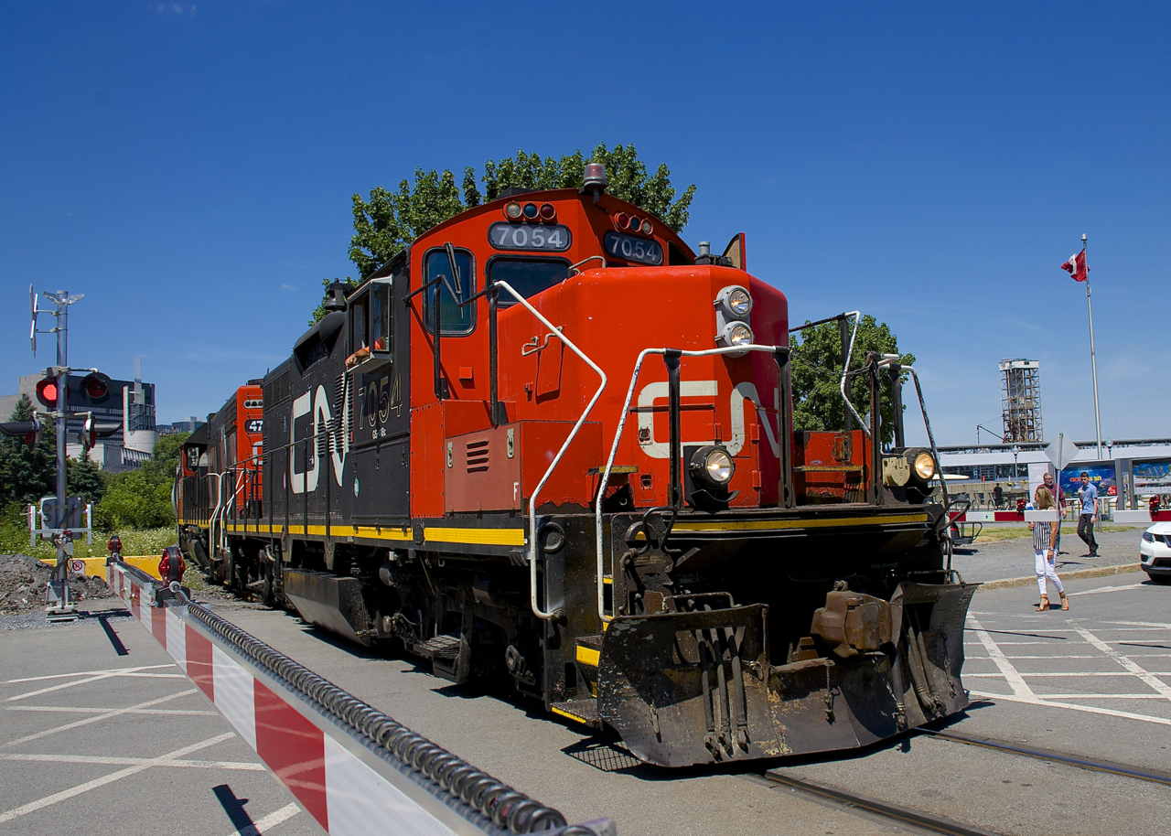 The Pointe St-Charles Switcher is leaving the Port of Montreal with nine cars and CN 7054 & CN 4707 for power. It is passing one of the many crossings in this area that now has crossing gates, in service for about two months now. Prior to that security had to flag all of the crossings.