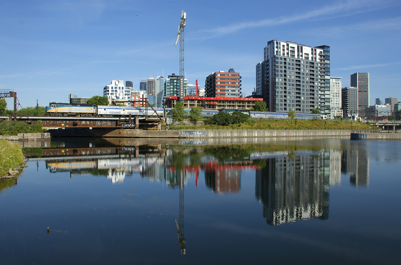 VIA 601 with VIA 6439 and two cars and VIA 603 with VIA 6455 and another two cars are joined as they pass the Peel Basin in Montreal.