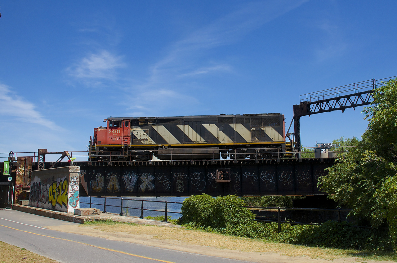 This section of CN's St-Hyacinthe Sub is normally passenger-only, with VIA Rail, Amtrak and RTM passenger trains passing over the Lachine Canal on the way to and from nearby Central Station. However once in a blue moon freight power will pass this way so that they can reverse towards the Victoria Bridge and wye their power and that is the case here. CN 527 arrived in Pointe St-Charles Yard with CN 2401 as the sole power, long hood forward. While waiting for the Pointe St-Charles switcher to arrive from the Port of Montreal with cars for them, they decided to wye their unit so that they could run to Taschereau Yard with the power running short hood forward. Here it is backing up over the Lachine Canal on the way to wyeing the power.