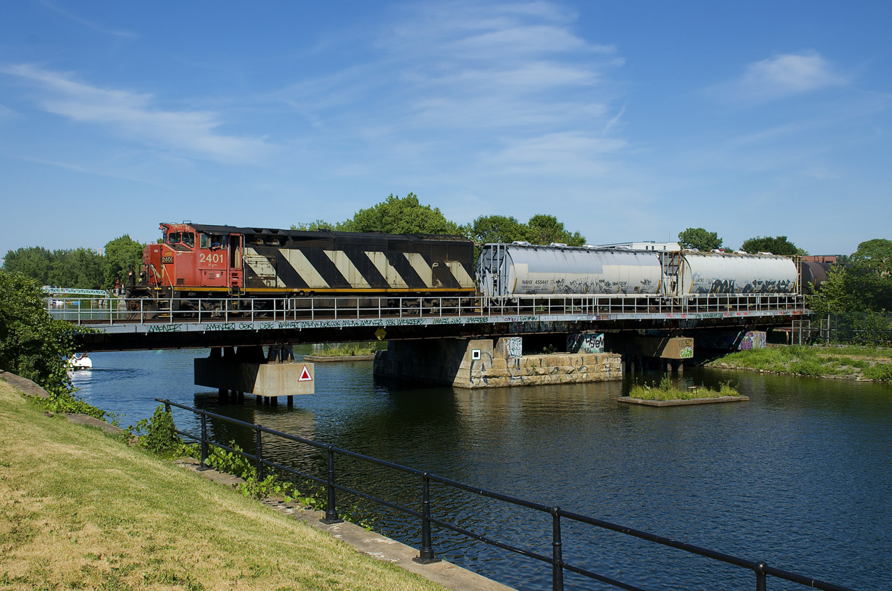 After setting off and lifting cars at Pointe St-Charles Yard, CN 527 is now departing for Taschereau Yard with CN 2401 and 60 cars as it crosses the Lachine Canal.
