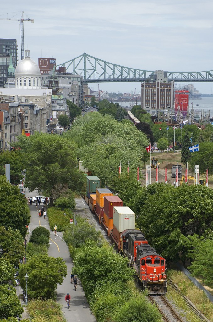 A CN transfer is leaving the Port of Montreal with CN 7054 & CN 4707 leading 56 cars, with intermodal up front and mixed freight behind it.