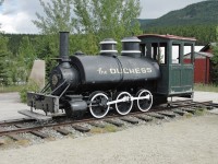 Displayed beside the WP&YR station at Carcross, Yukon Territory<br>
"The Duchess" is a saddle tank loco built by Baldwin in 1878 as an 0-6-0 for a Vancouver Island coal mine that had 30" track gauge.  Sources indicate that the front coupling rods were removed in 1883 turning it into a 2-4-0, and it has been that way ever since.  Around 1889 it was re-gauged for 36" track. <br><br>
In the past, the main travel corridors of Yukon Territory were its lakes and rivers, which WP&YR connected with.  In 1900 Duchess was acquired to power the Atlin Short Line Railway (a.k.a. Taku Tram), replacing horses, and the line became a White Pass & Yukon property that same year.  It pulled a single coach on the 2 mile inter-lake portage between docks at the east of Taku Arm off Taglish Lake and Scotia Bay on Atlin Lake BC - in the other direction it pushed.   After a 20 year career it was retired and shipped back to Carcross YT, where it's boiler  at times served as a trash incinerator, until the engine was put on display in 1931.<br>"The Duchess" was cosmetically restored a few years ago, including a new wooden cab.
