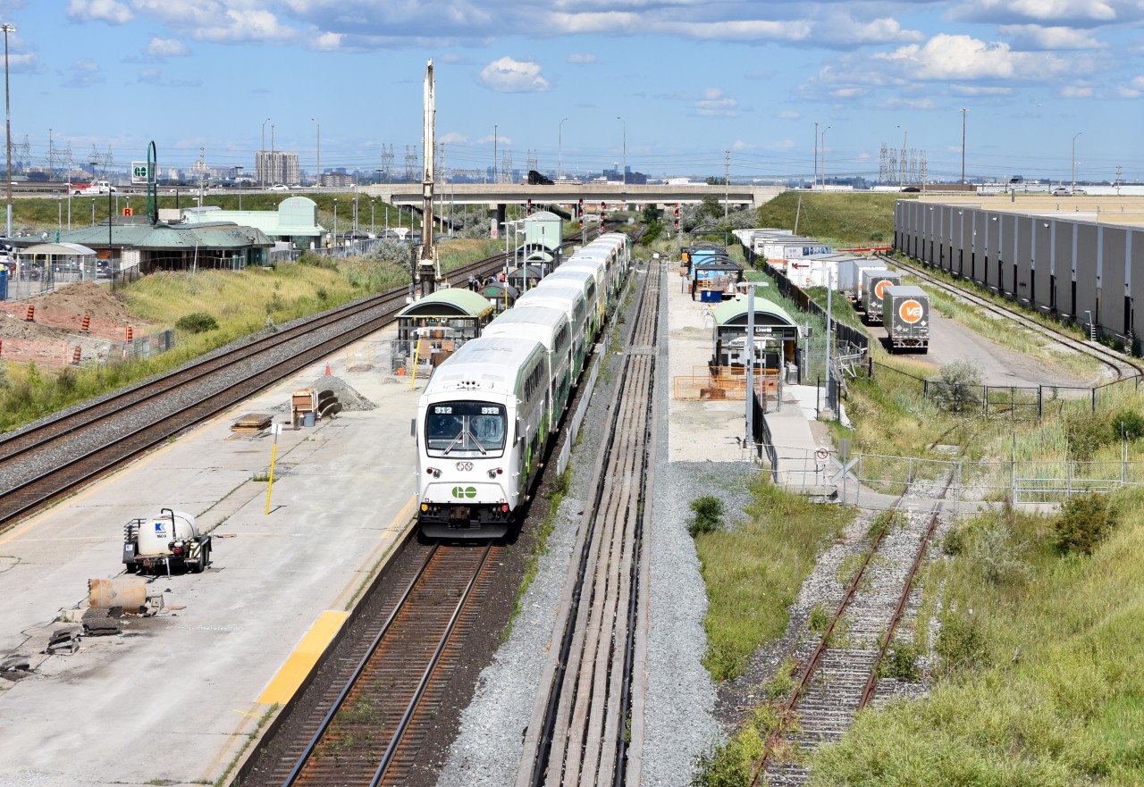 The 4:15 GO train arrives at Bramalea GO to let quite handful of passengers off who are coming home from Toronto as it is just about the start of evening rush hour.   If you look to the right on the track #4 platform you can see that a lot of progress has been made in the platform expansion project over the last few months and if you look to the left of the train you can also see that part of the track #2&3 platform is closed off due to construction as the railway hopes to expand the platforms to be able to accommodate the 12 car GO trains as well as improve the bus shelters by adding heat and air conditioning so they will be more comfortable for passengers waiting for the train. It’s nice to finally see some progress being made because for the last couple years it didn’t look like much was being done. Construction for this project began very early in 2015 and from what I remember the railway hoped to have it finished sometime in 2017 but in mid-2018 it’s still going but nice to see the progress being made. Hopefully the passengers will find the long wait worth it in the end.   Sad for us railfans though, the spur that curves to the right serving the factory right next to the GO Station (Kuehne + Nagel) shows no sign of use being that the fence that separates the passengers from the construction who wish to access the south parking lot goes right over the tracks on the right hand side of the small walkway to the south parking lot.