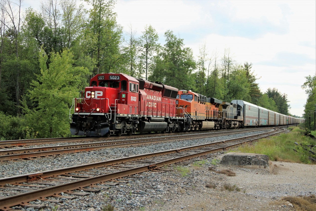 Once in a while having an eastbound running  late, (6:15 pm),  is a good thing. The bright sunshine during the day was making way for rain and a very helpful cloud gave me a chance to get this shot. CP 5023 leads BNSF 8107 and CSX 346 off the Galt sub main and on to the South track as they enter Guelph Junction with 6600 feet of auto racks.