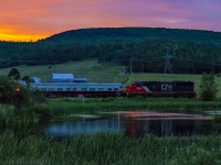 In the nice glow of a fiery sunset, test train O998 passes McCullys pond, just east of the now shut down Potash Corp facilities. 