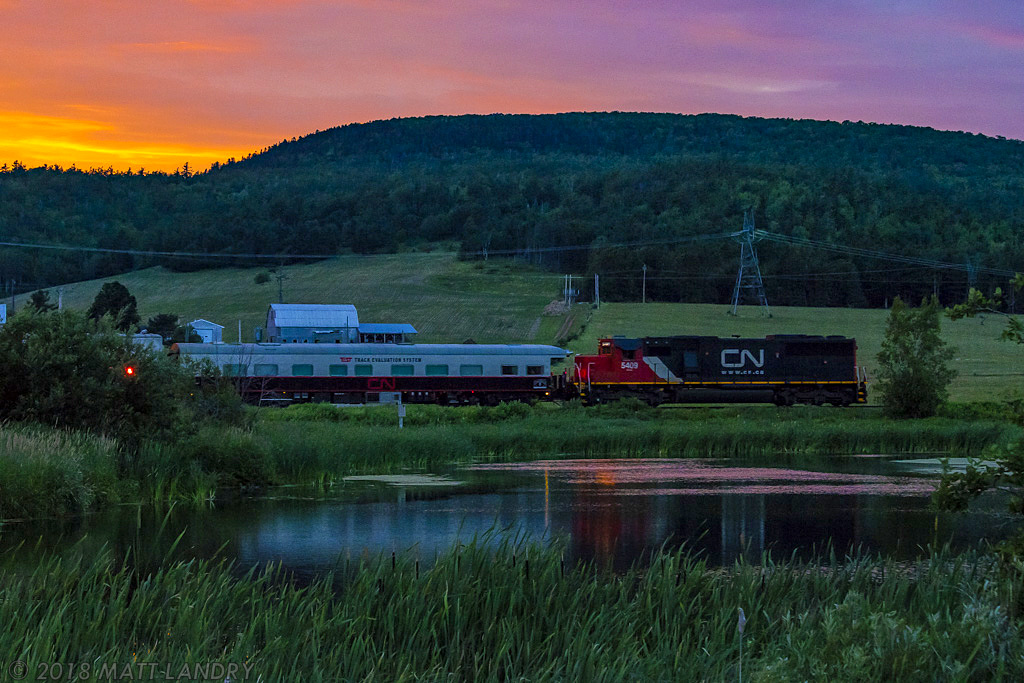 In the nice glow of a fiery sunset, test train O998 passes McCullys pond, just east of the now shut down Potash Corp facilities.