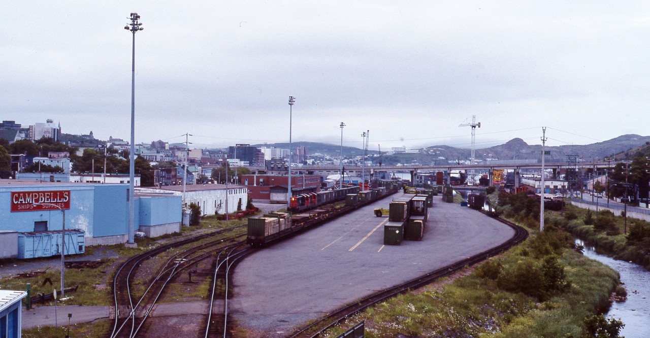 YESTERDAY'S YARD - As viewed from the bridge crossing the tracks, Terra Transport Extra 936 West with three units and about twenty containers prepares to depart the St. John's Yard for Port aux Basques late on the grey evening of July 28, 1988. Knowing that time was quickly running out for the Newfoundland operations, this was the among some of the very last full length revenue trains to operate westbound and the very last to be captured by the photographer. Despite the pristine condition of the NF210's, within eight weeks they would be shut down for good on the Island, with lead 936 being preserved at Avondale, 941 sold to F.C. del Pacifico of Nicaragua and 919 being scrapped.