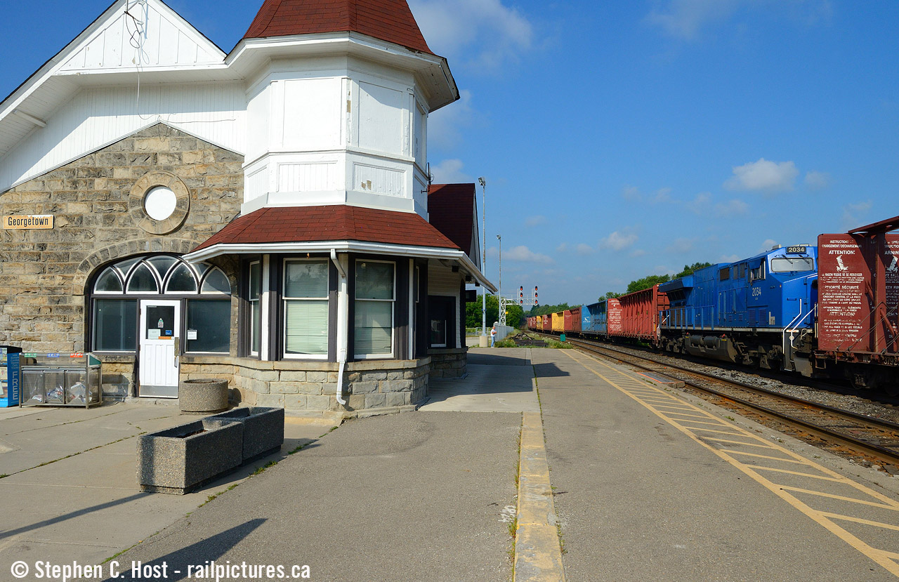 Georgetown was one of my favourite towns as a child, and I have family history here. Not surprising  my favourite childhood towns involved some form of railways: Georgetown, Brampton, and Streetsville :) Built in 1858 by the Grand Trunk, this handsome stone structure is used for both GO and VIA services, with space inside for a GO agent. But the station seems to lack air conditioning and is inhospitable in the morning owing to a greenhouse effect, but at least it's still open for easy washroom access. A small group of us used to go here frequently in the early 2000's (Matt Watson, Brian Switzer, Shane Murphy, Marcus Stevens amongst others) and now a new group seems to frequent the station, it's a nice quiet place to watch trains.
This is a detour train, called 373 and it was an otherwise calm windless, but hot morning until this train entirely of centrebeams passed at track speed. I'd certainly say this train made an efficient fan, kicking winds upwards of 50 MPH, threatening to blow over someone's tripod setup. In the lead was a CN GEVO, with 70 or so empty centrebeams , the DPU as you see here, and 60+ more empty centrebeams, the "fan train" as I dub it did a good job keeping us cool as it passed by, during this unusually hot and sunny Ontario summer.  Thank god it cooled off this weekend, instead of gallivanting about this weekend for more photos in the rain, I'm taking a nice break and catching up on posting some pictures amongst other chores :) Cheers all.
