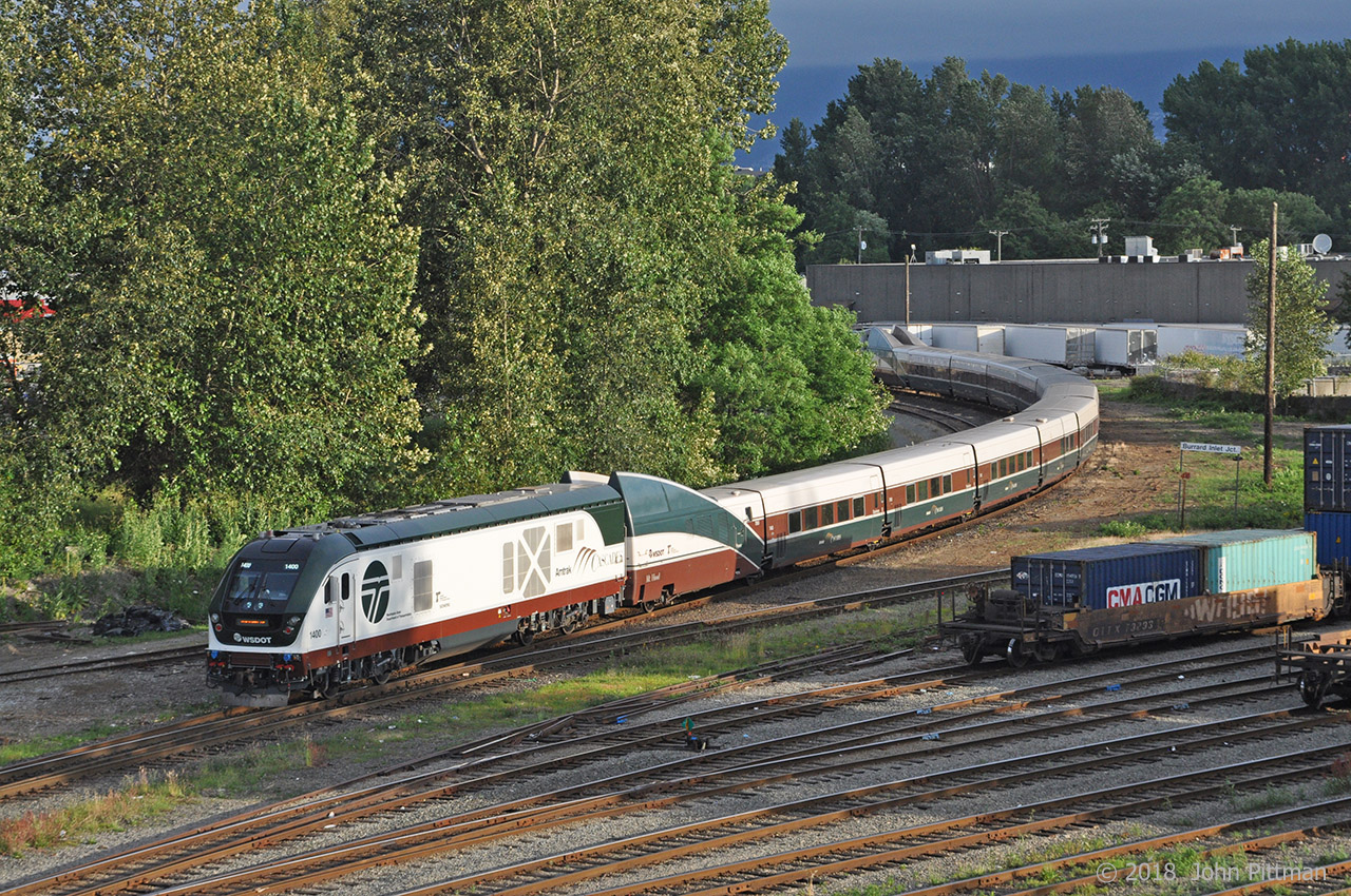 Amtrak Cascades train 517, the 6:35am departure from Vancouver BC's Pacific Central station is leaving station track.  Its locomotives and Talgo coach-set closely match another Cascades train that derailed at a curve near DuPont in Washington state on 18 December 2017, part of that train falling onto I-5. 
In the lead today is Siemens SC-44 "Charger" diesel electric locomotive AMTK 1400 with Washington State DOT (WSDOT) and Oregon DOT lettering, and the Mt. Hood Talgo trainset in the Cascades paint scheme.  A GE P42DC "Genesis" AMTK 85 in ordinary Amtrak scheme is at the rear (it lead into Vancouver).  Note the short articulated sections and single axle wheelsets of the passively-tilting Talgo coach-set. The end transition sections with HEP and baggage compartment were styled to merge with F59PHi locomotives originally purchased for Cascades service.
The accident train was lead by AMTK 1402 (scrapped), with the Mount Adams Talgo coach-set (scrapped), and trailing AMTK 181  (stayed on rails, back in service).  The 18 Dec 2017 mishap occurred on the inaugural revenue run over the recently upgraded Point Defiance bypass.  The final NTSB report is pending, but entering a 30 mph limit curve at 78 mph is always a bad idea. There were 3 fatalaties and numerous injuries, from minor to very serious, and at least $40 million in property damage.  I was told that Talgo trainsets were removed from Cascades service after the accident, until cleared of blame.