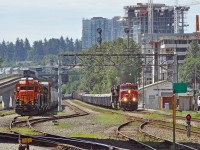 One train approaching, one at rest, one receding.<br>
The approaching CN freight lead by CN 3059 and CN 3060 is heading north-east past BNSF's New Westminster freight station on one of the 2 hot tracks, while BNSF GP39m 2826 (EMD turbo 12-645 and AR10 generator in GP30 body) rests in a siding ahead of BNSF 3149 (GP25), BNSF 2112 (GP38 in BN green), and their train. A Millenium Line Skytrain is heading away toward Sapperton station.<br><br>
The CN train probably crossed the Fraser River on the CN/BNSF New Westminster swing bridge from Port Mann-Surrey minutes earlier. It will continue on the New Westminster sub, following the track north-west at the wye just east of my vantage point at Braid Street grade crossing. Based on its railcars, my guess is that the CN train will branch off for North Vancouver through the Thornton Tunnel and over the Second Narrows rail bridge. (Vancouver downtown yards and south Burrard Inlet port mostly handle intermodal containers and grain.)
