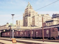 This image from a color negative shows CN boxcars at Toronto Union Station in June 1972. In the background is the Royal York hotel.