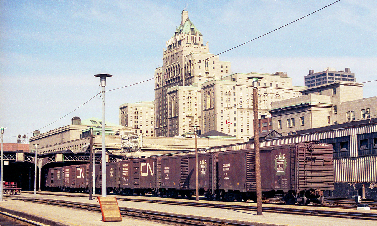 This image from a color negative shows CN boxcars at Toronto Union Station in June 1972. In the background is the Royal York hotel.