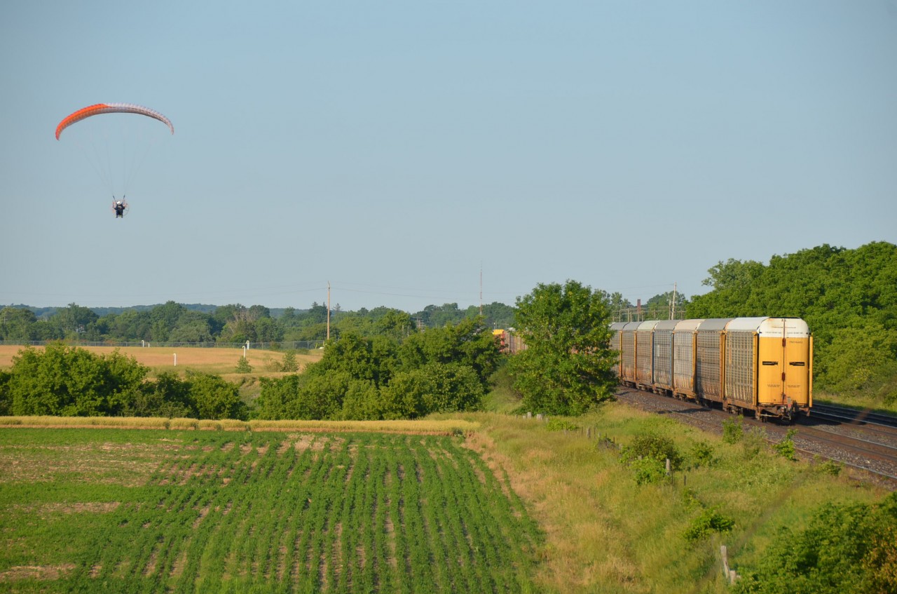 Photographed on CRHA Niagara's "Longest Day" event in 2016 (a 37 year tradition to go out rail-fanning on the Friday closest to the longest day of the year); we couldn't help but admire the ingenuity of this railfan's method of getting a more interesting photographic angle by using a powered parachute. Train itself was CN 2299 and 2512 followed by a long line of mostly autorack cars.