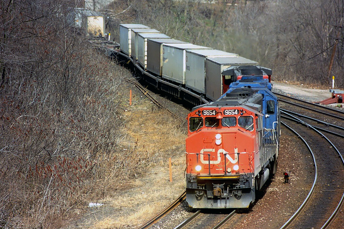 So I found Part 2 which was actually part 1. The Hotshot ran around the other westbound at Bayview to lead it up the hill. The second unit is a Conrail GP38-2; foreign power being pretty rare in those days. It seems odd ot see TOFC in well cars, but that is where they began in Canada; CN "Laser" service.