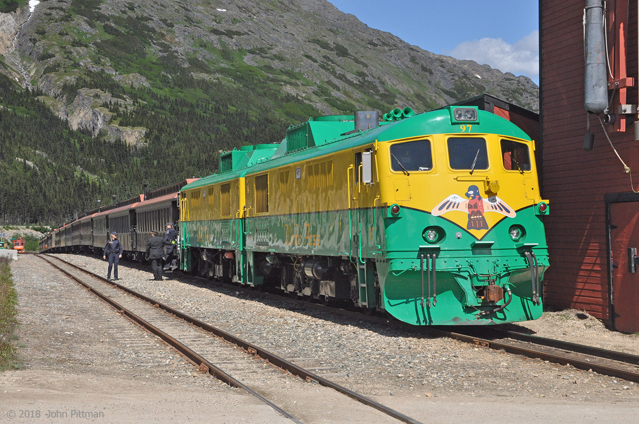 WP&Y 91 with WPY 97 pulled the midday train north from Skagway AK to Fraser BC - one of the world's most scenic train rides.  Now WP&Y 97 is in the lead after coupling onto the other end of the train for the return to Skagway.  The CBSA officers who verified the admissibility of inbound passengers for entry to Canada are having a brief chat with the WP&Y conductor, before walking back to the Yukon Highway border post. 
All de-training passengers (but one) are boarding their buses to continue their journeys. I'll be there shortly!  Once the inbound passengers have gone, busloads of Skagway-bound passengers will board.