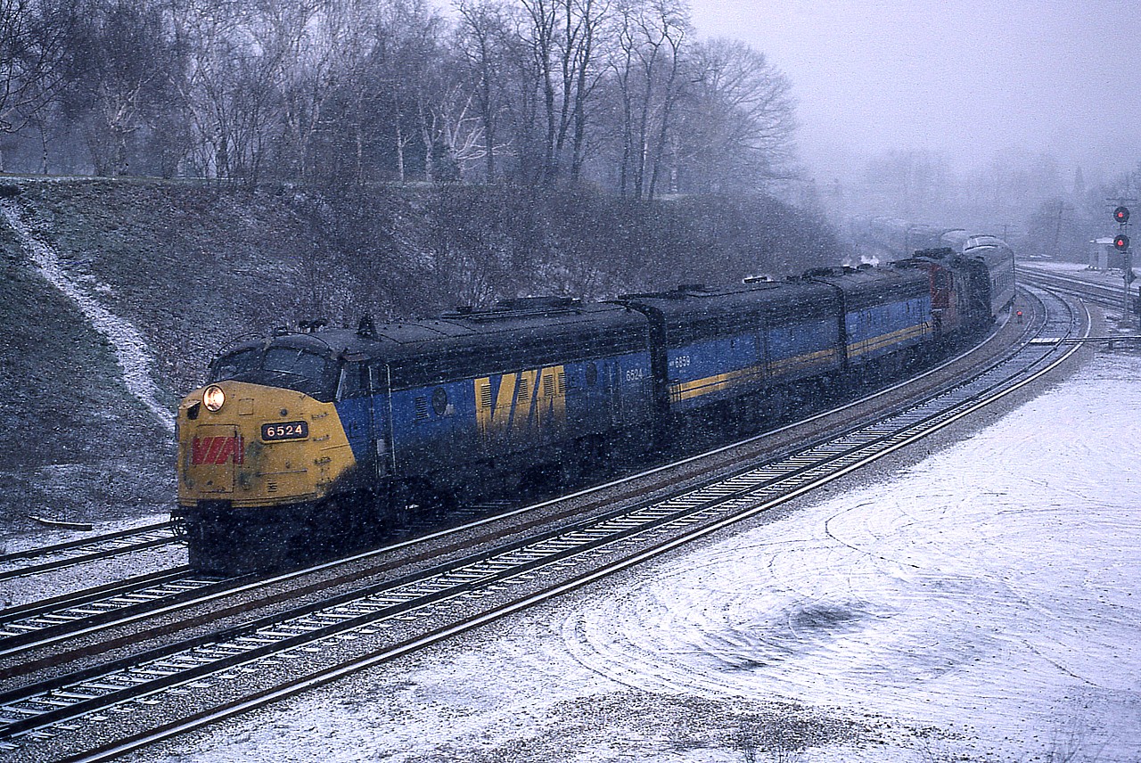 Oh wouldn't you know it, a late winter 'snowstorm' started up as I waited out VIA's dinner-hour #75 westbound thru the Junction on an April 8th.an otherwise gloomy afternoon. The snow actually enhances the scene. I have recorded VIA 6524, 6659 and 6637 but omitted the last unit, a CN. Oh well. Car count a bit obscured by the fresh snow. Current railfans' hangout, the walkbridge, is barely visible in the background.