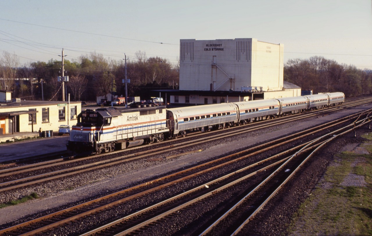 What did Nat King Cole sing: "Roll out those lazy, hazy, crazy days of summer...You'll wish that summer could always be here!" Let's take a look at what one would see 25 years ago at Aldershot on a typical summer's evening.

Our first photograph is VIA Train 98, "the Maple Leaf" from New York. Tonight, it is powered by a GP40TC, acquired from GO Transit in 1988.