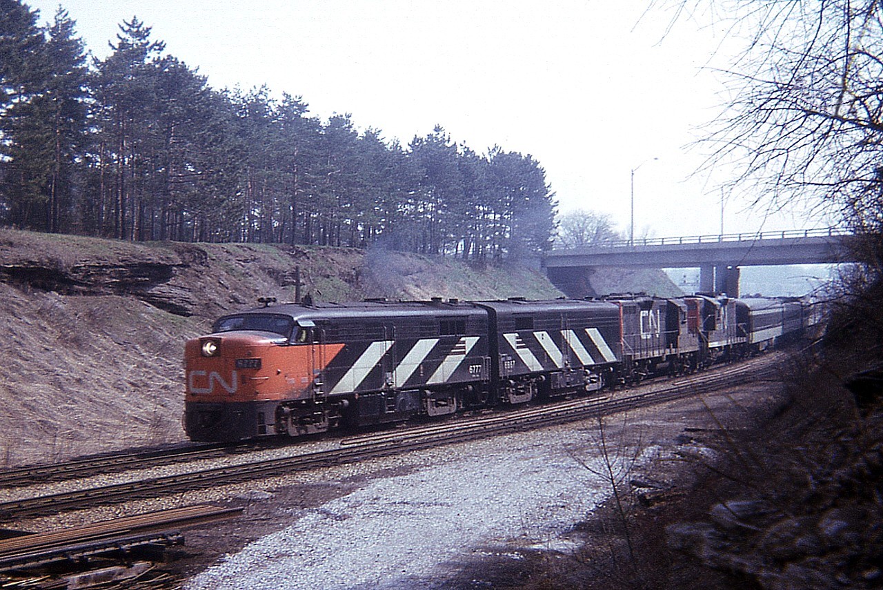 For me, this shot is a long time ago.  I had been into this 'train photography' barely a month when I shot this, and VIA wasn't even born. It was before the days of the now ever-present notebook, and so numbers are not recorded; just the date on the image. CN 6777, "B" unit and a pair of CN geeps pull dinner time train #75 around the bend at Bayview Junction on a decent (for photography)but overcast Sunday. This image shows the train rolling under the York Blvd bridge at Hamilton West. Not much has changed here from this setting in the past 44+ years. The MLW FPA-4 #6777 is now operating on the Cuyahoga Valley in Ohio.