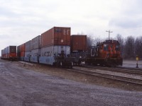 Here’s one for the modelers…A low-tech double stack intermodal terminal next to a road in small town Ontario. Norfolk & Western/Norfolk Southern operated the Dain City intermodal terminal (off St. Clair Drive) in the Welland area until October 1998. Maersk double stack service from Tacoma, Washington started in April 1988 using NS to Chicago and Union Pacific to the west coast. K-Line traffic was also handled through this terminal, according to articles in the Journal of Commerce (go to www.joc.com and search “Canadian double stack service Canada”; also see NiagaraRails.com). In this April 1989 photo, we see CN SW1200RS 1385, the Dain City yard engine, passing stack cars.