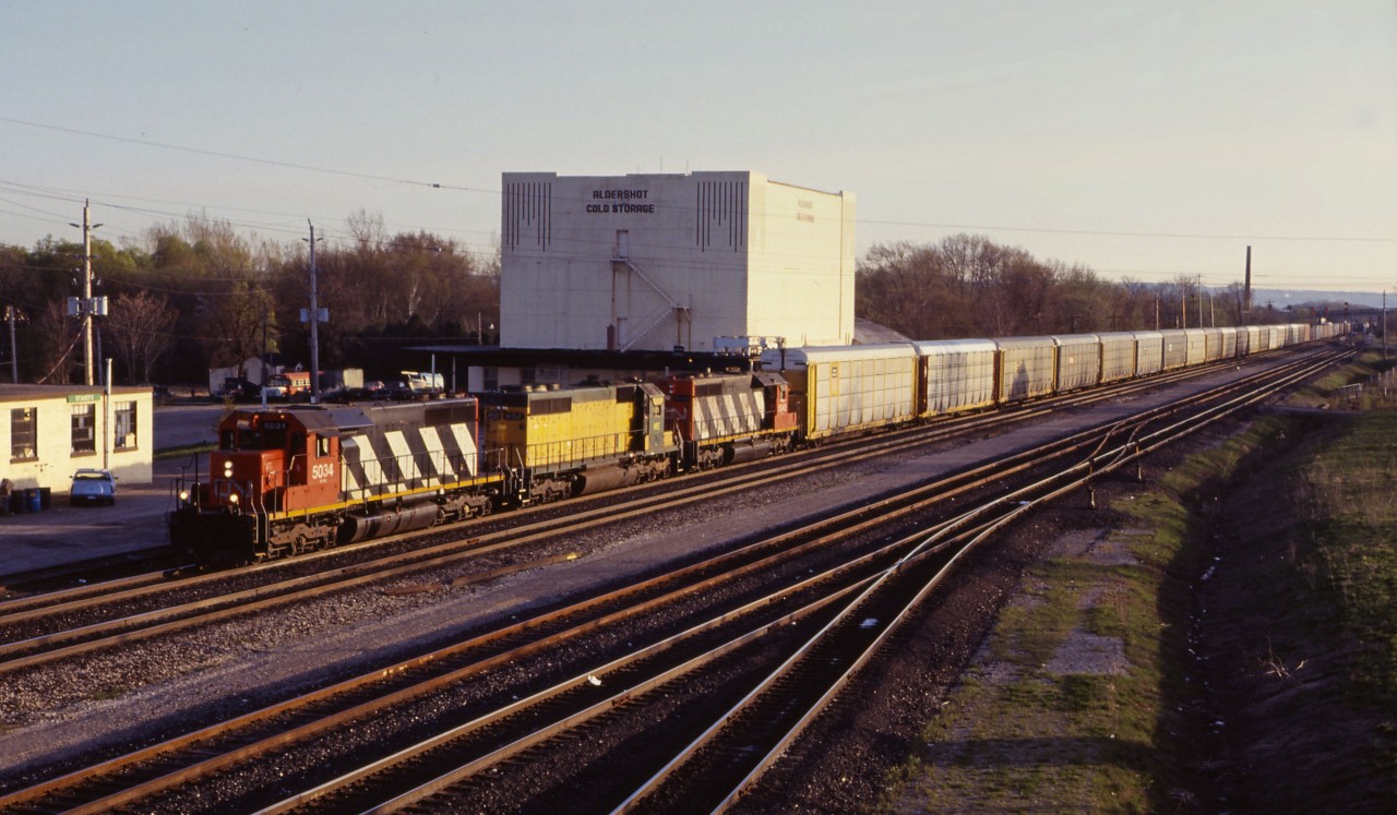 A trio of SD40s lead an eastbound past the Aldershot Cold Storage, a landmark which graced many railfan pictures over the years. CN 5034, leased NRE 892 (ex-CNW) and CN 5040 power this train which has a good amount of auto traffic in the form of "racks" and parts cars, in addition to some general merchandise.