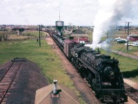 In the Spring of 1958, Canadian National Railways’ transition of its locomotive roster from steam to diesel-electric is nearing completion.  Inasmuch as steam’s final scheduled run on the CNR won’t occur for another two years, on the company’s transcontinental Beachburg and Alderdale Subdivisions between Ottawa, North Bay and Capreol Ontario, the torch is being passed to the next generation of motive power.  With GMD-built FP9A and F9B units well established in passenger service on the Super Continental and the Continental for the past three years, it’s now time for regular freight service through the Upper Ottawa Valley to experience a similar transition, with mainline 2-8-2 Mikado, 2-10-2 Santa Fe, 4-8-2 Mountain and 4-8-4 Northern “Type” steam power yielding the hi-iron to modern and more efficient GMD F7A & GP9, MLW FA-1, RS-3 & RS-18, and CLC (Fairbanks-Morse designed) CFA16-4, CFB16-4, & H16-44 diesel-electric engines.
<br>
<br>
On May 27, 1958, at Pembroke, Ontario, railway enthusiast and avid photographer Stephan Delmonte “Del” Rosamond is on hand to witness and photo-archive Valley railway history in the making, as Class U-2-e “Northern Type” 4-8-4 engine CN 6179 becomes the last steam locomotive to work through Pembroke in regular freight service over CN Lines.  Engine 6179 is the last of an order of fifteen Northerns built by Montreal Locomotive Works in 1940.  Sadly the locomotive would be scrapped at the London Reclamation Yard later the same year on the 7th of November, not much more than five months after Del witnessed the engine’s final passage through the Valley.
<br>
<br>
The train is operating in the eastward direction towards Ottawa, and is viewed from an elevated walkway located part way up the coaling tower.  Given the presence in the consist of flatcar loaded Model CD-52 transit buses, produced by Canadian Car & Foundry (CC&F) in Fort William for the City of Montreal, the movement likely originated at Port Arthur as Train No. 408.
<br>
<br>
The depot seen in the picture, for many years, displayed a station name board which read “Pembroke Jct”.  At some point, following the October 1956 termination of regular passenger service on the 21.1 mile Locksley Subdivision between the downtown “Pembroke” station and the hamlet of Golden Lake, the name board on the outer station was changed to “Pembroke”.  The location likely owed its “Pembroke Jct” distinction to the fact that a connecting track - seen diverging from the main line just west of the station - tied the former Canadian Northern Railway (CNoR) Pembroke Subdivision with former Pembroke Southern Railway trackage at National Jct. a short distance away and less than a mile from the end of track in downtown Pembroke.  Inasmuch as everything was rolled into Canadian National Railways in 1923, the “Jct” component on the name board was retained for another three-and-a half decades.  In Del’s photograph, the Locksley Subdivision’s main track can be seen in the distance on embankment near the Muskrat River beneath the steel trestle at the rear of the freight train.  It would be abandoned in the Fall of 1960.
<br>
<br>
By 1963, with the regular service steam-era officially ended on the CNR Lines three years earlier, the water tank seen in Del’s photograph had been demolished, along with the coal tower upon which Del stood to compose his picture.  In the summer of 1965 the wood-frame station building was demolished and replaced by a modern single-story brick structure that survived until the late 1990s.  Today (summer of 2018), other than the distant steel trestle which stands devoid of rail, nothing of a railway nature remains where Stephan “Del” Rosamond once bid adieu to mainline steam in the ‘Heart of the Upper Ottawa Valley’.
<br>
<br>
Raymond S. Farand
