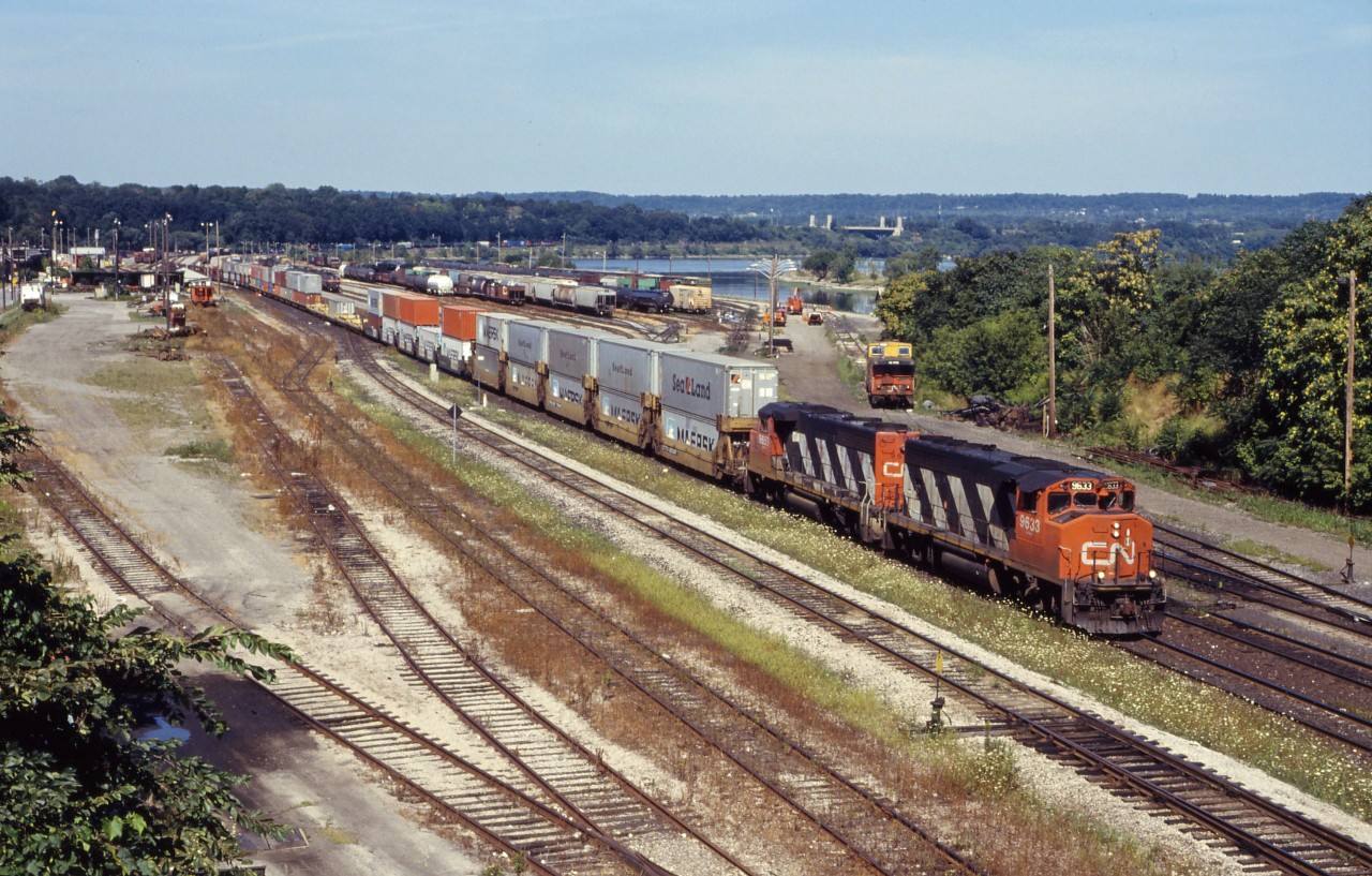 We don’t normally associate double-stack container trains with Hamilton and the Niagara Peninsula; however, from February 1989 until double stack clearance projects were completed through Western Canada in the early 1990s, CN operated double-stack service between Toronto and Vancouver via Buffalo. Initially 12 “5-pack” car sets were leased from TTX. Later in the year (July 1989), Maersk introduced service between Tacoma, Washington and Toronto/Montreal, also via CN in the Niagara Peninsula and NS west of Buffalo. Two units typically handled this train--today, a pair of GP40-2Ws (9633 and 9659).