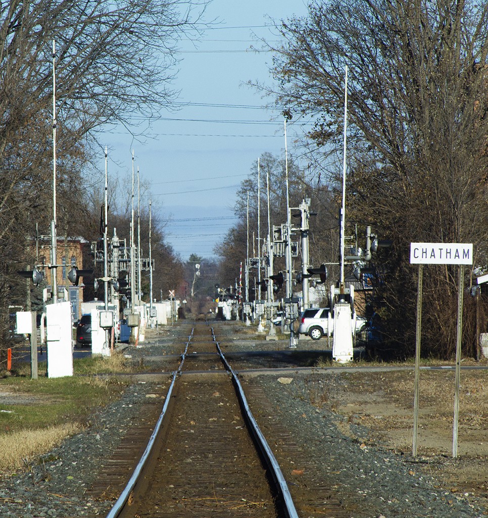 Since moving to Chatham, this scene has always amazed me. This is the CP rail corridor through the heart of Chatham. One has to wonder how there has not been any major derailment through here, as numerous properties both residential and commercial butt right up to the track. But we also have to ponder what this scene looked like in 'yester-year'. Whether it is today or yesterday, it is still a marvel at how trains can tie up the local traffic through 17 level crossings between Bloomfield Road in the west and Prince Albert Drive in the east. And when train time does arrive, what a scene it is with a sea of flashing red ad lowering gates.


Of note, the 'Chatham' name sign marks the city limit for eastbounds. You can also make out the row of brick buildings to the left that line William Street. Just across the street used to sit the old station, now relocated. And if one looks way down the line in the distance, we still see the signal arm that stands to this day letting westbound trains know what to do next as they clear the old yard and used t cross over the diamond with the CSX's former Subdivision #2.